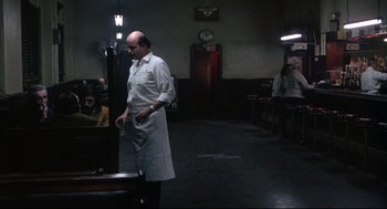 Movie still from “The Friends of Eddie Coyle” (1973), directed by Peter Yates – A man standing in a room with a knife in his hand; Wide shot, High angle