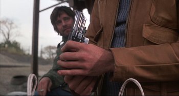 Movie still from “The Friends of Eddie Coyle” (1973), directed by Peter Yates – A man holding a bunch of knives in his hands; Close Up shot, Low angle