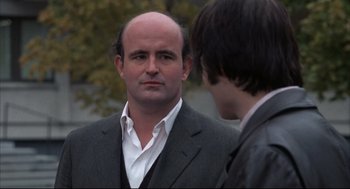 Movie still from “The Friends of Eddie Coyle” (1973), directed by Peter Yates – A man in a suit and tie talking to another man in a suit and tie; Close Up shot, Over the shoulder angle