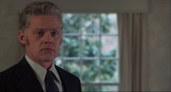 Movie still from “The Friends of Eddie Coyle” (1973), directed by Peter Yates – A man in a suit and tie in front of a window; Close Up shot, Low angle