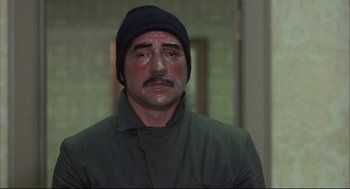 Movie still from “The Friends of Eddie Coyle” (1973), directed by Peter Yates – A man in a black hat and a green jacket; Close Up shot, High angle