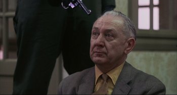 Movie still from “The Friends of Eddie Coyle” (1973), directed by Peter Yates – An older man wearing a suit and tie; Close Up shot, Over the shoulder angle