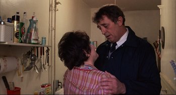 Movie still from “The Friends of Eddie Coyle” (1973), directed by Peter Yates – A man and a woman are hugging in a room; Medium shot, Over the shoulder angle