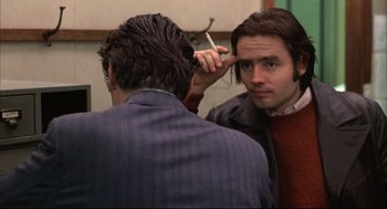 Movie still from “The Friends of Eddie Coyle” (1973), directed by Peter Yates – A man is looking at himself in the mirror while holding a cigarette; Close Up shot, Over the shoulder angle