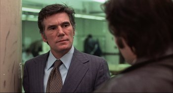Movie still from “The Friends of Eddie Coyle” (1973), directed by Peter Yates – A man wearing a suit and tie in front of a mirror; Close Up shot, Over the shoulder angle