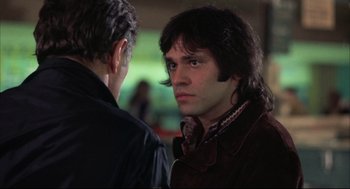 Movie still from “The Friends of Eddie Coyle” (1973), directed by Peter Yates – A man with long dark hair is looking at the camera; Close Up shot, Over the shoulder angle