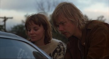 Movie still from “The Friends of Eddie Coyle” (1973), directed by Peter Yates – A man and a woman standing next to each other near a car; Close Up shot, Low angle