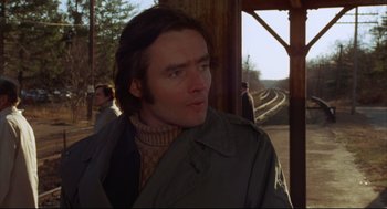 Movie still from “The Friends of Eddie Coyle” (1973), directed by Peter Yates – A man in a trench coat standing next to a train track; Close Up shot, Low angle