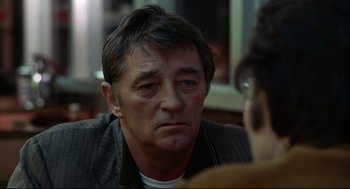 Movie still from “The Friends of Eddie Coyle” (1973), directed by Peter Yates – A person sitting in front of another person; Close Up shot, Over the shoulder angle