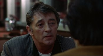 Movie still from “The Friends of Eddie Coyle” (1973), directed by Peter Yates – A person sitting at a table; Close Up shot, Over the shoulder angle