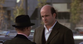 Movie still from “The Friends of Eddie Coyle” (1973), directed by Peter Yates – A man with a bald head talking to another man wearing a hat; Close Up shot, Over the shoulder angle