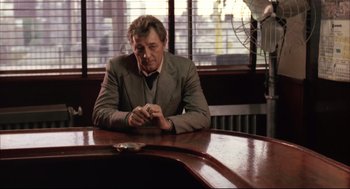 Movie still from “The Friends of Eddie Coyle” (1973), directed by Peter Yates – A man sitting at a table in front of a window; Medium shot, Over the shoulder angle