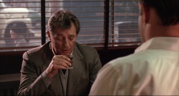 Movie still from “The Friends of Eddie Coyle” (1973), directed by Peter Yates – A man in a suit and tie drinking from a cup; Medium shot, Over the shoulder angle