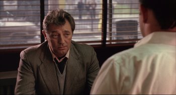 Movie still from “The Friends of Eddie Coyle” (1973), directed by Peter Yates – A person wearing a suit and tie; Close Up shot, Over the shoulder angle