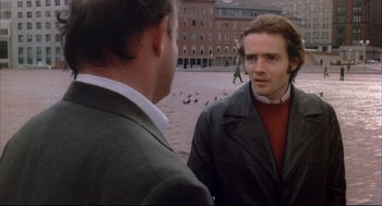 Movie still from “The Friends of Eddie Coyle” (1973), directed by Peter Yates – Two men are standing in a plaza with pigeons in the background; Close Up shot, Over the shoulder angle