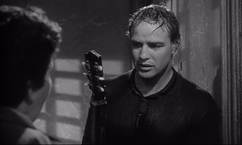 Movie still from “The Fugitive Kind” (1960), directed by Sidney Lumet – A black and white photo of a man holding a guitar; Close Up shot, Over the shoulder angle