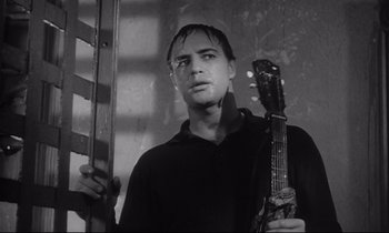 Movie still from “The Fugitive Kind” (1960), directed by Sidney Lumet – A black and white photo of a man holding a guitar; Close Up shot, Low angle