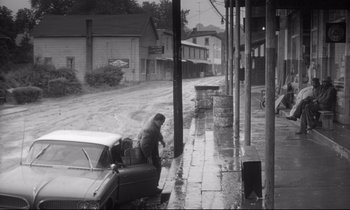 Movie still from “The Fugitive Kind” (1960), directed by Sidney Lumet – An old photo of a man standing next to an old car; Wide shot, High angle