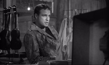 Movie still from “The Fugitive Kind” (1960), directed by Sidney Lumet – A black and white photo of a man looking at a computer screen; Medium shot, Over the shoulder angle