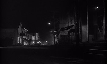 Movie still from “The Fugitive Kind” (1960), directed by Sidney Lumet – A black and white photo of a city street at night; Extreme Wide shot, Low angle