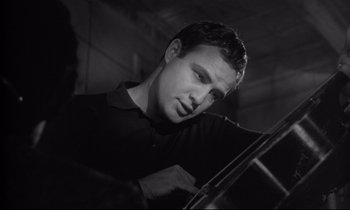 Movie still from “The Fugitive Kind” (1960), directed by Sidney Lumet – A black and white photo of a man holding a violin; Close Up shot, Low angle
