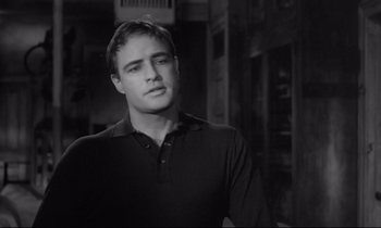 Movie still from “The Fugitive Kind” (1960), directed by Sidney Lumet – Black and white photograph of a man in a black shirt; Close Up shot, Over the shoulder angle