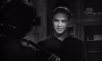 Movie still from “The Fugitive Kind” (1960), directed by Sidney Lumet – A young man holding a stick in a room; Close Up shot, Over the shoulder angle