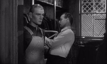 Movie still from “The Fugitive Kind” (1960), directed by Sidney Lumet – A man is helping another man put on a suit; Medium shot, Over the shoulder angle