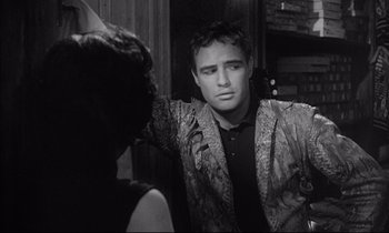 Movie still from “The Fugitive Kind” (1960), directed by Sidney Lumet – A black and white photo of a man in a suit and tie; Medium shot, Over the shoulder angle