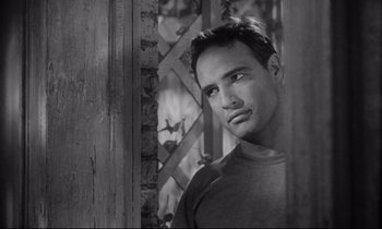 Movie still from “The Fugitive Kind” (1960), directed by Sidney Lumet – Black and white photograph of a man looking at the camera; Close Up shot, Over the shoulder angle