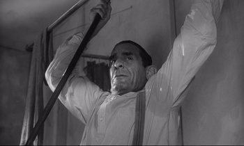 Movie still from “The Fugitive Kind” (1960), directed by Sidney Lumet – A man holding a cane up to his head; Medium shot, Low angle
