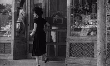 Movie still from “The Fugitive Kind” (1960), directed by Sidney Lumet – A woman walking down the sidewalk in front of a store; Wide shot, Low angle