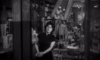 Movie still from “The Fugitive Kind” (1960), directed by Sidney Lumet – A black and white photo of a woman standing in a store; Medium shot, Over the shoulder angle