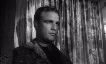 Movie still from “The Fugitive Kind” (1960), directed by Sidney Lumet – Black and white photograph of a man in front of a curtain; Close Up shot, Low angle