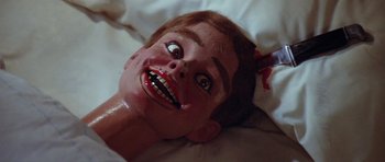 Movie still from “The Funhouse” (1981), directed by Tobe Hooper – A creepy doll with a red hair and a red nose; Close Up shot, High angle