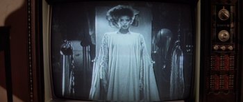 Movie still from “The Funhouse” (1981), directed by Tobe Hooper – A woman in a white dress standing in front of a mirror; Medium shot, Low angle