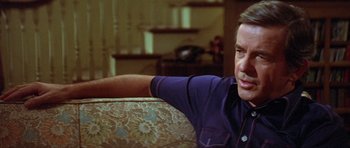 Movie still from “The Funhouse” (1981), directed by Tobe Hooper – A person sitting on a couch near a window; Close Up shot, Over the shoulder angle