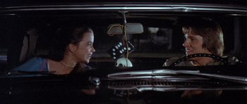 Movie still from “The Funhouse” (1981), directed by Tobe Hooper – A woman sitting in the back seat of a car at night; Medium shot, Over the shoulder angle