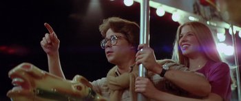 Movie still from “The Funhouse” (1981), directed by Tobe Hooper – A man in glasses and a scarf is riding a carousel; Close Up shot, Low angle