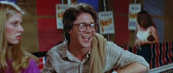 Movie still from “The Funhouse” (1981), directed by Tobe Hooper – A person wearing glasses and smiling; Close Up shot, Over the shoulder angle