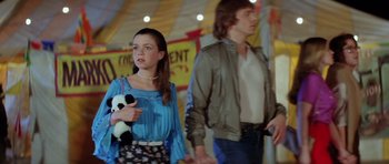 Movie still from “The Funhouse” (1981), directed by Tobe Hooper – A woman holding a panda bear while standing next to a man; Medium shot, Over the shoulder angle