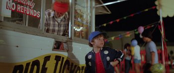 Movie still from “The Funhouse” (1981), directed by Tobe Hooper – A boy and a girl are standing in front of a ticket booth; Medium shot, Over the shoulder angle