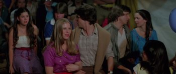 Movie still from “The Funhouse” (1981), directed by Tobe Hooper – A man and a woman sitting next to each other in front of a crowd; Medium shot, Over the shoulder angle