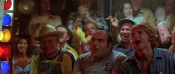 Movie still from “The Funhouse” (1981), directed by Tobe Hooper – A group of people sitting in front of a microphone; Medium shot, High angle