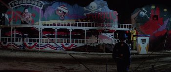 Movie still from “The Funhouse” (1981), directed by Tobe Hooper – A man standing next to a boat with a pirate mural on it; Extreme Wide shot, Low angle
