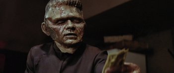 Movie still from “The Funhouse” (1981), directed by Tobe Hooper – A person wearing a mask and holding money; Close Up shot, Low angle