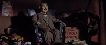 Movie still from “The Funhouse” (1981), directed by Tobe Hooper – An old doll sitting in a chair with a bag; Medium shot, High angle