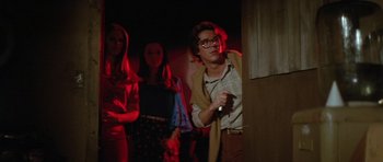 Movie still from “The Funhouse” (1981), directed by Tobe Hooper – A group of people standing in a dark room; Medium shot, Low angle