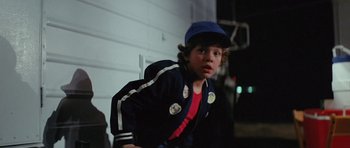 Movie still from “The Funhouse” (1981), directed by Tobe Hooper – A young boy wearing a baseball cap and jacket; Medium shot, Over the shoulder angle