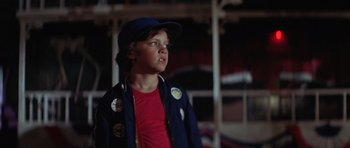 Movie still from “The Funhouse” (1981), directed by Tobe Hooper – A boy in a baseball cap and jacket looking up; Medium shot, Low angle